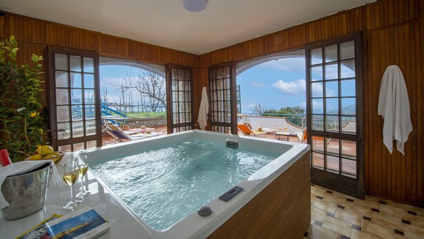 A room with a large bathtub, wooden walls, and large windows. - Elegant & Panoramic Villa with Sea View Solarium (Furore)