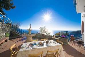 Une terrasse avec une table préparée pour le petit-déjeuner, offrant une vue panoramique sur la mer.