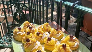 A green plate with pastries on a balcony overlooking a coastal town.