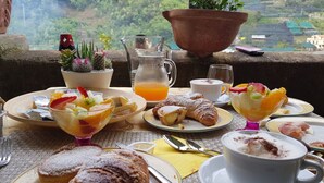 Desayuno con diferentes platos, una jarra de zumo de naranja y una vista panorámica.