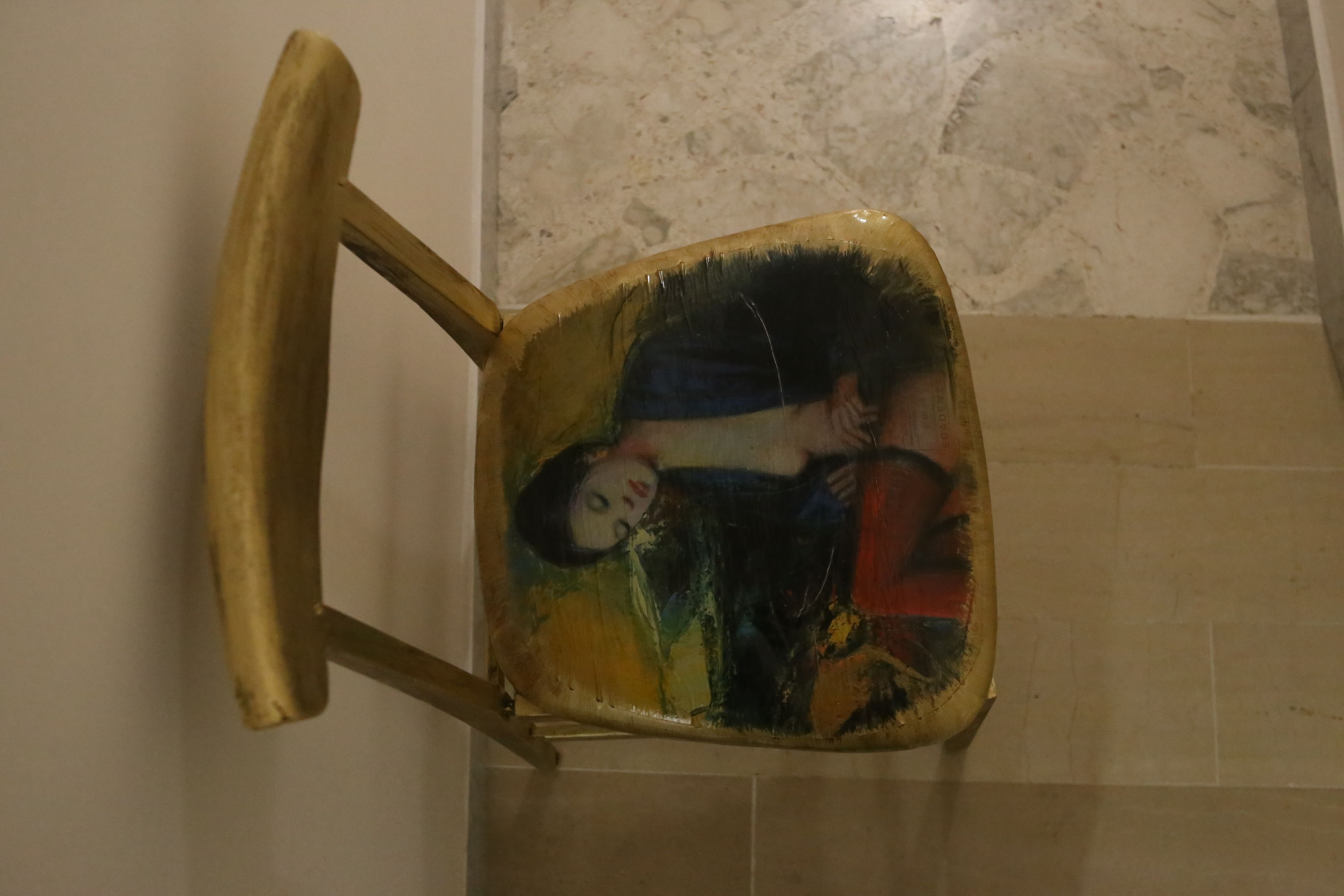 Une chaise ornée d’un tableau coloré représentant une personne.