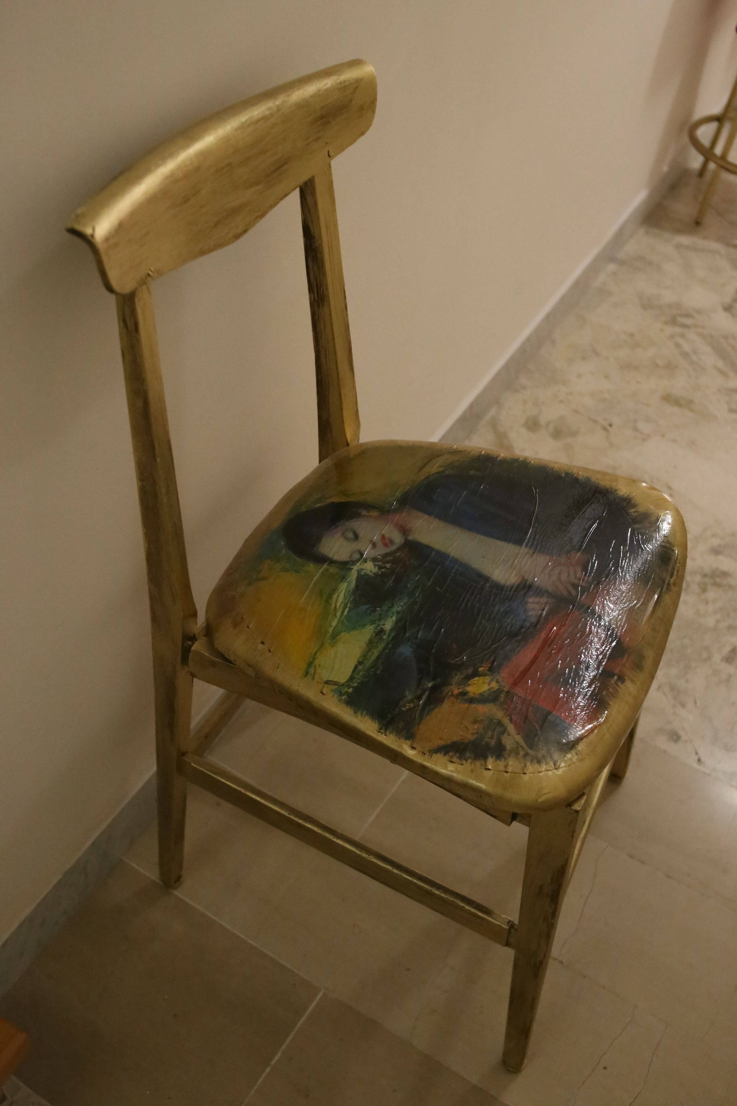 Una silla de diseño único, con un asiento pintado y un respaldo de madera.