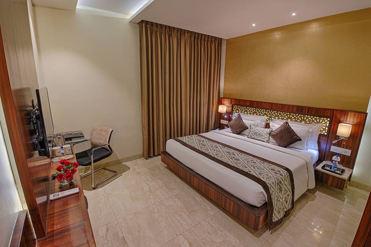 Una habitación de hotel con una cama grande, un escritorio con silla, televisión y baño.
