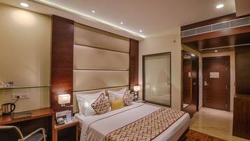 A hotel room with a large bed, bedside tables, a desk, and a wardrobe.