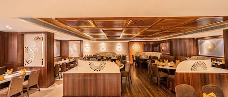 A restaurant with wooden paneling, multiple dining tables, and a central bar area.
