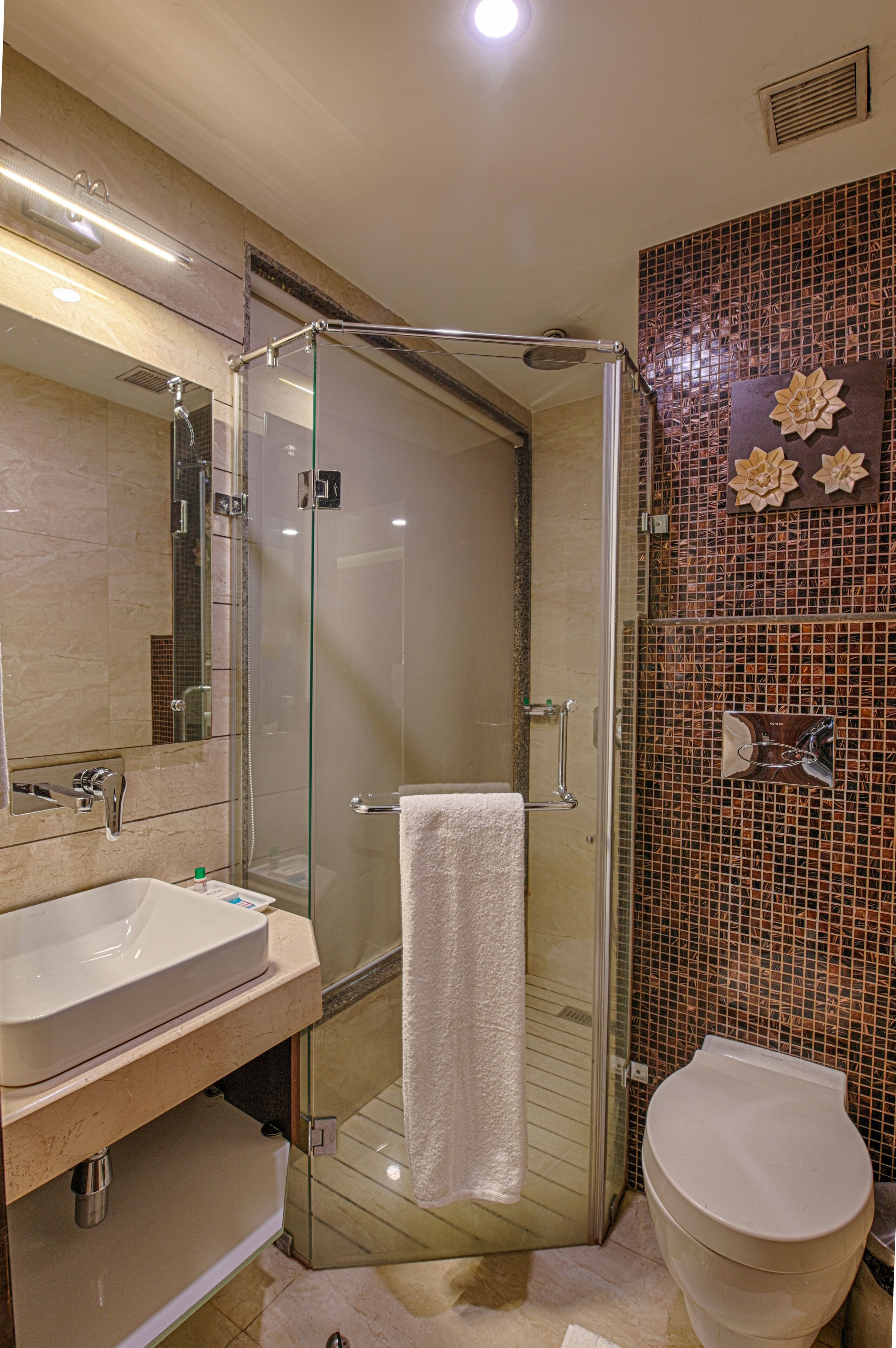 A modern bathroom with a glass-enclosed shower, a white sink, and a toilet.