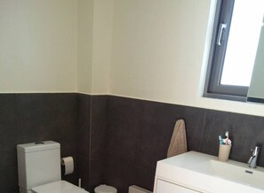 Een badkamer met toilet, wastafel en een handdoek aan de muur.