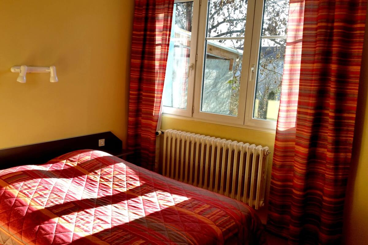 A room with a bed, a radiator, and a window with curtains.