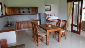 Una cocina moderna con armarios de madera, un comedor con mesa y sillas de madera, y un dormitorio con cama y ventana.