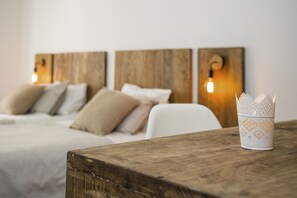 A neatly made bed with a wooden headboard, a white chair, and a table with a white candle holder. - Casa Maca Guest House Boutique - Adults Only (Barcelona)