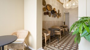 A hallway with wicker furniture, a patterned floor, and decorative wall art. - Casa Maca Guest House Boutique - Adults Only (Barcelona)