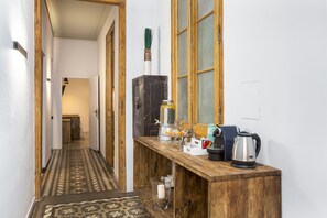 A narrow hallway with a patterned floor leading to a room. A wooden counter with a kettle and a coffee maker is visible. - Casa Maca Guest House Boutique - Adults Only (Barcelona)