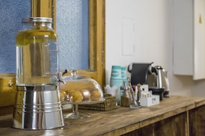 Un piano di lavoro in cucina con una macchina da caffè, un barattolo e un contenitore coperto pieno di cibo.