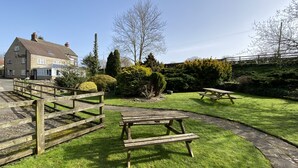 Un jardin avec des tables de pique-nique et un escalier en pierre menant à un bâtiment.