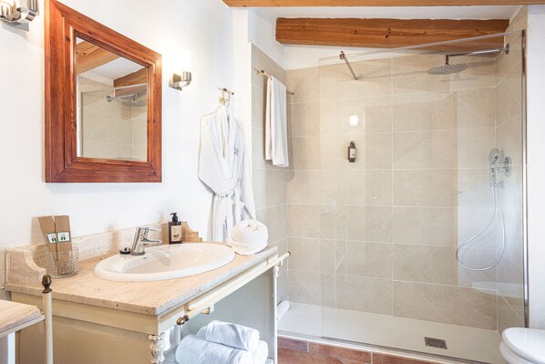 A bathroom with a wooden vanity, a large mirror, a glass shower enclosure, and a toilet. - Hotel Nord (Estellencs)