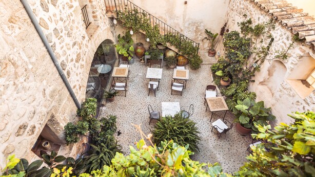 A courtyard with stone walls, potted plants, and outdoor seating. - Hotel Nord (Estellencs)