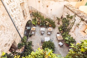 A courtyard with stone walls, potted plants, and outdoor seating. - Hotel Nord (Estellencs)