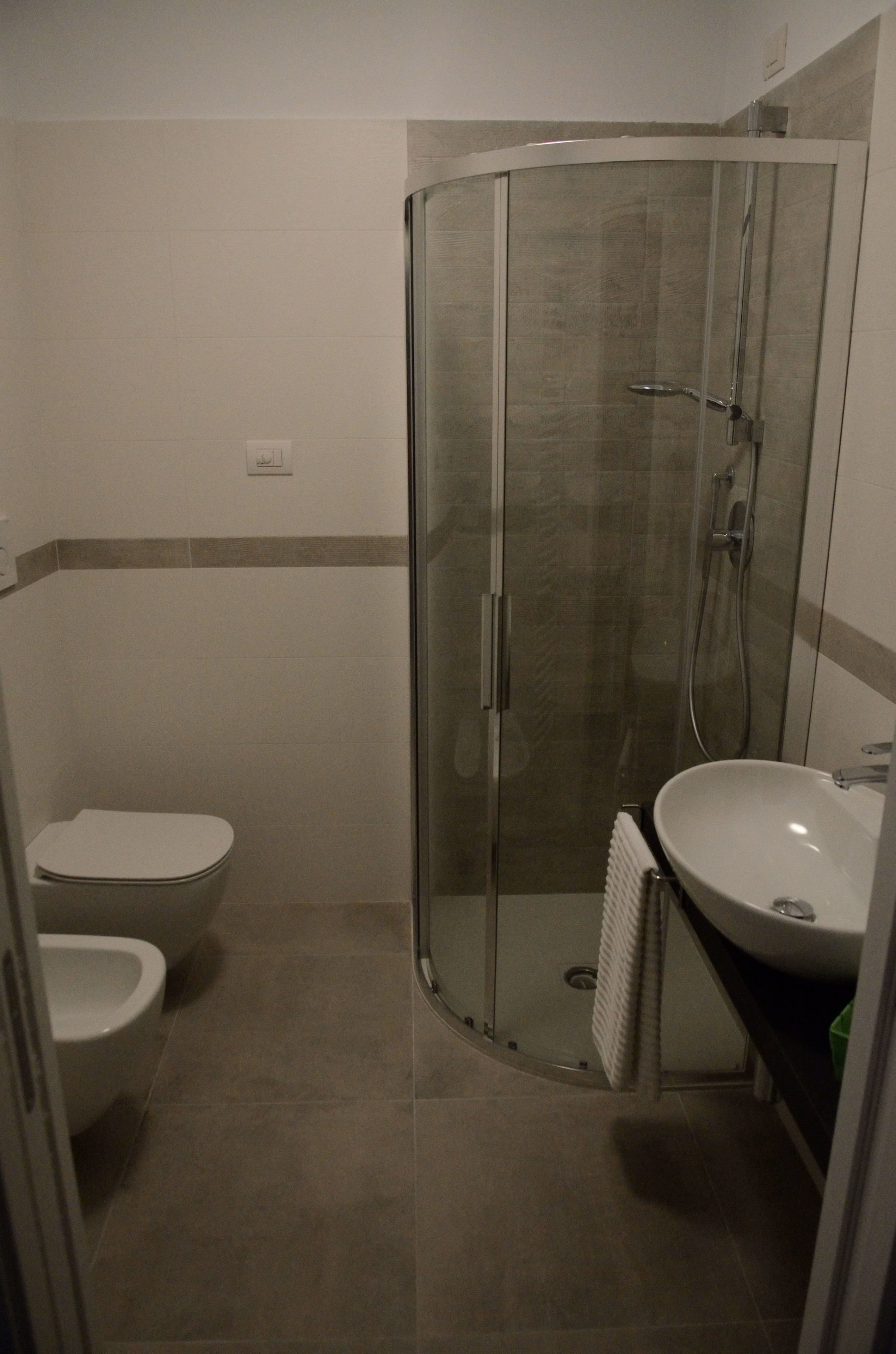 Un baño con ducha de vidrio, inodoro y lavabo.