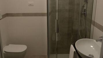 Un baño con ducha de vidrio, inodoro y lavabo.