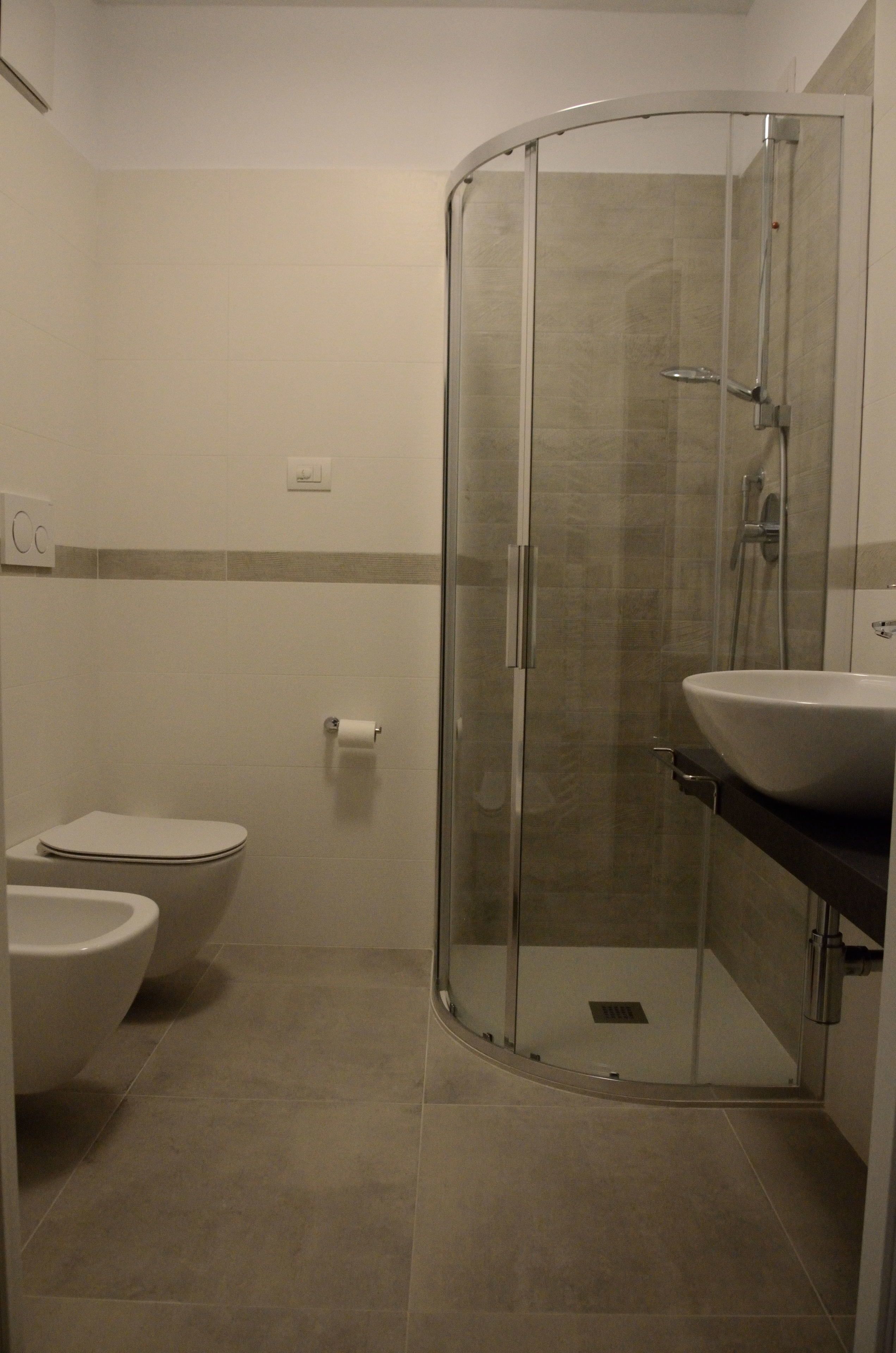 Un baño con ducha envuelta en vidrio, inodoro y lavabo.