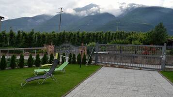 Un patio con dos sillones, una cerca de metal y vistas a las montañas.