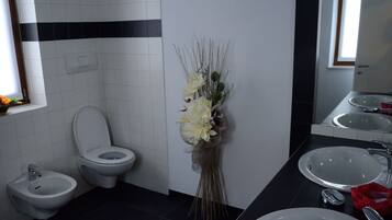 Een badkamer met toilet, bidet en twee wasbakken.