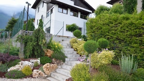 Una casa blanca con una escalera de piedra que lleva a la entrada, rodeada de plantas y arbustos.