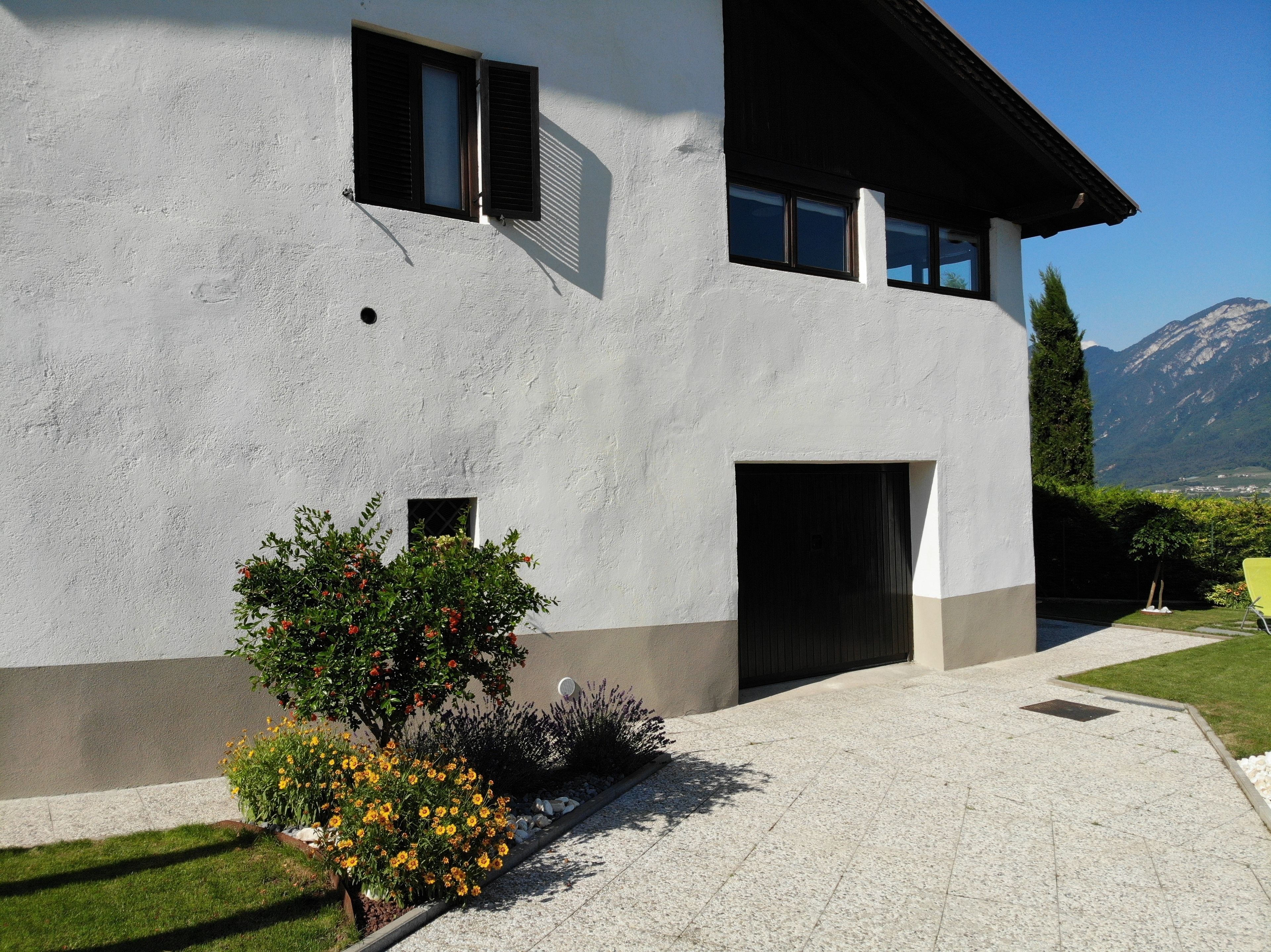 A modern two-story building with a white facade, a garage entrance, and a view of mountains in the background.