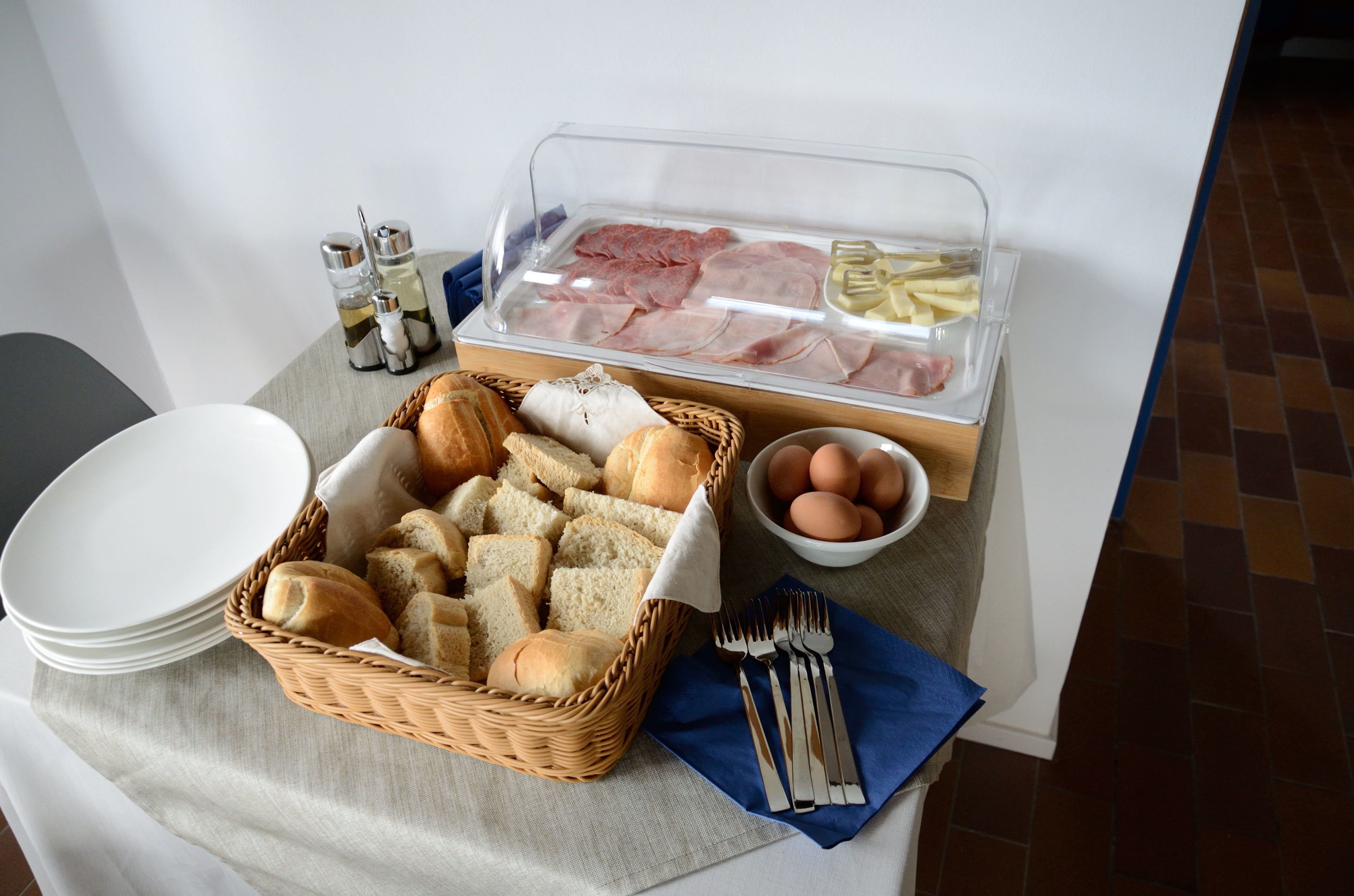 A breakfast buffet setup with bread, eggs, and various meats.