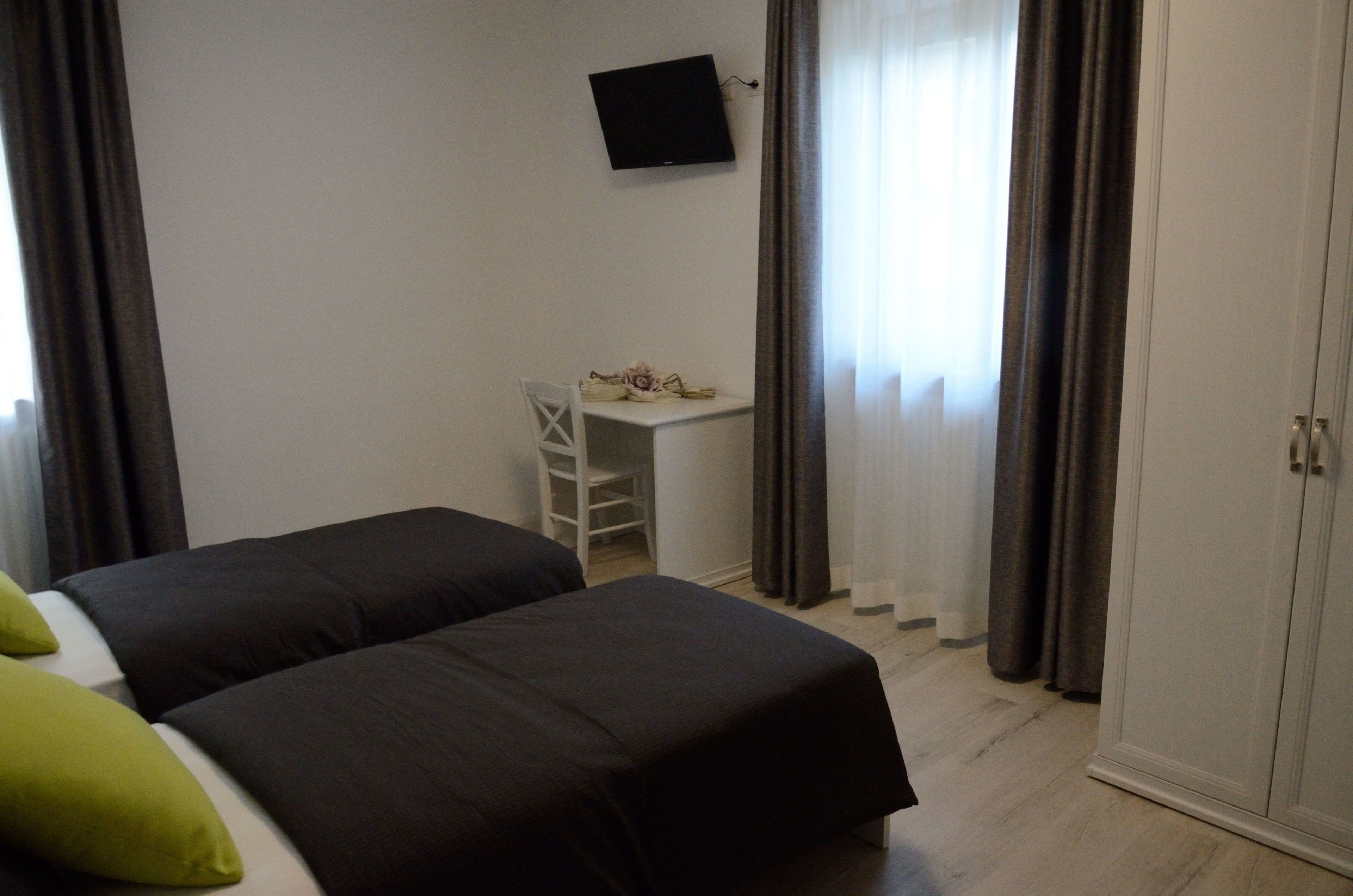 A bedroom with two beds, a desk, a TV, and a wardrobe.