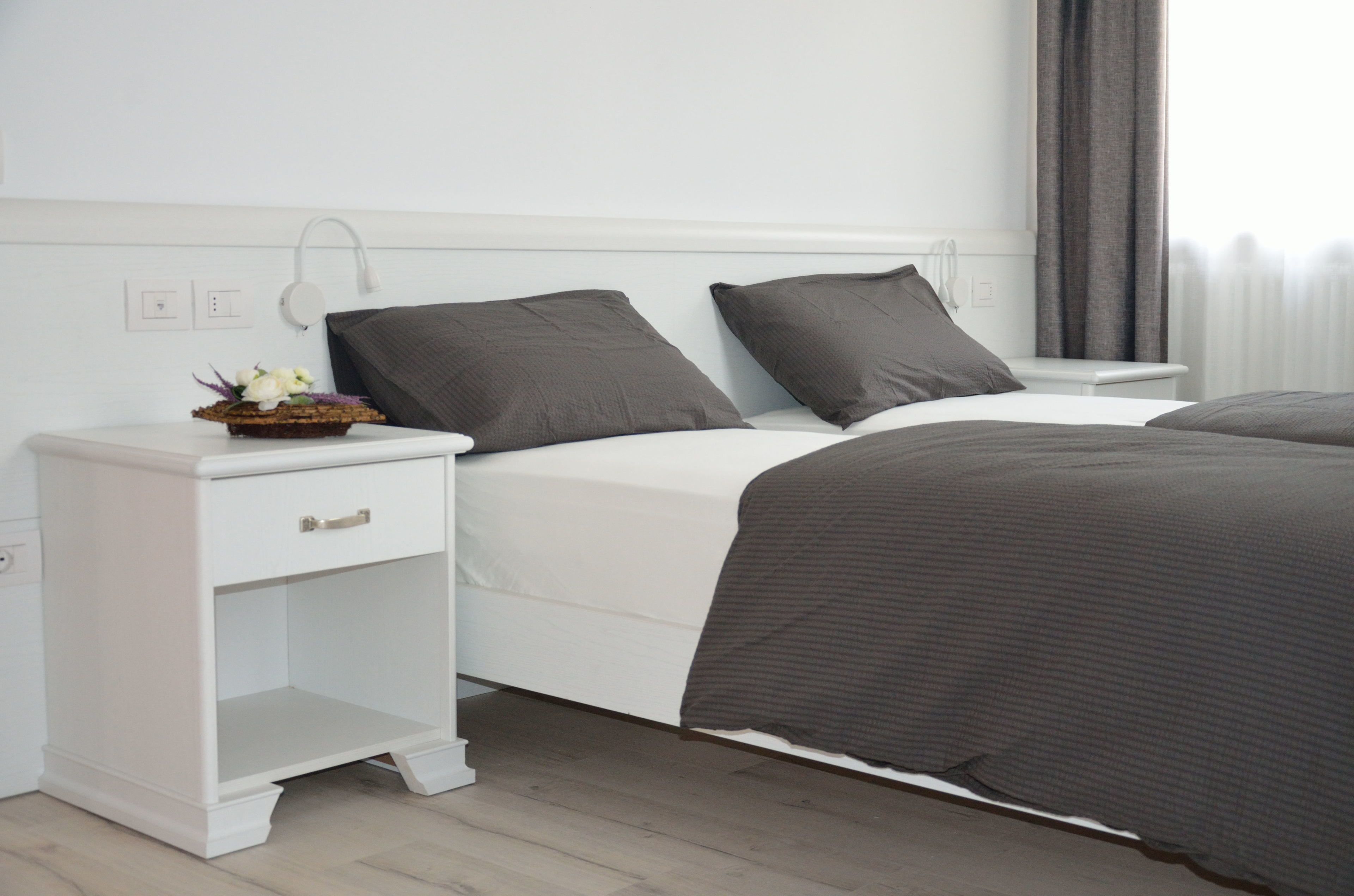 Ein ordentlich eingerichtetes Schlafzimmer mit einem Bett, Nachttischen und einem Schreibtisch.