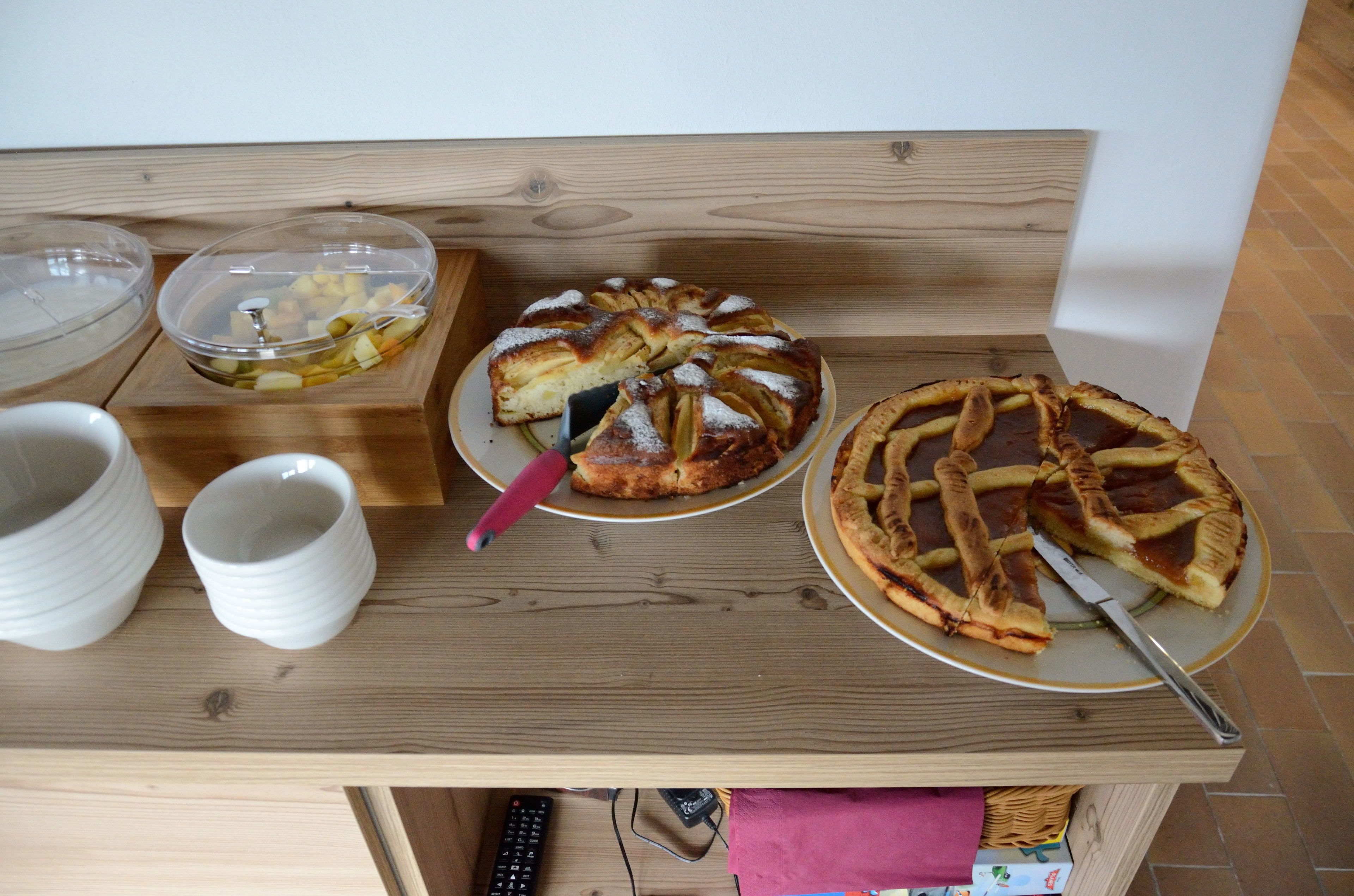 A wooden table with three dishes, two white cups, and a remote control.