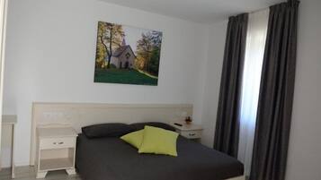 Una camera da letto con un letto, un comodino, una lampada e un quadro raffigurante una chiesa appeso al muro.