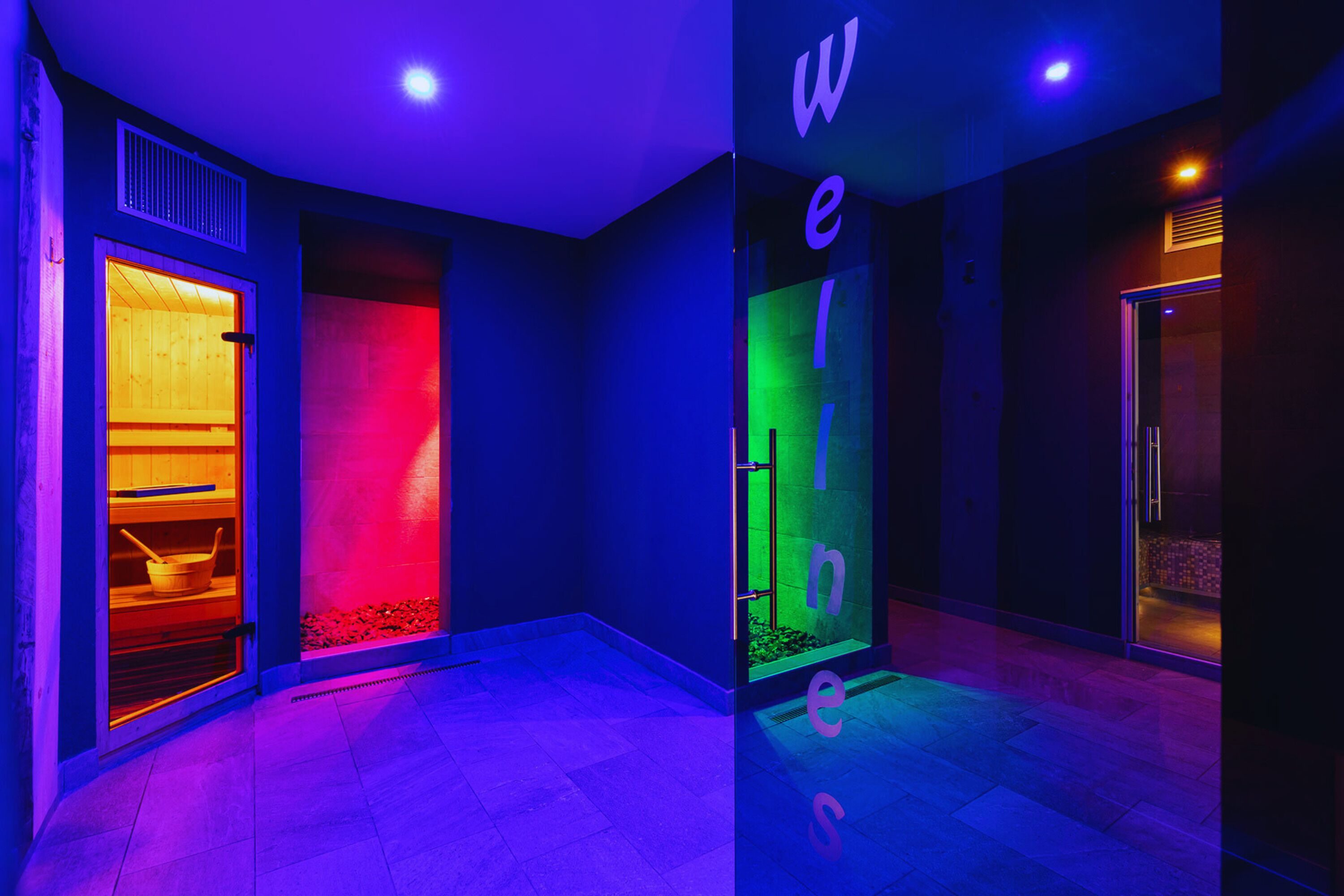 Um hall de hotel moderno com uma parede de cores mutáveis e uma área de recepção visível.