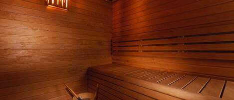 Una sauna con bancos de madera y un cubo.