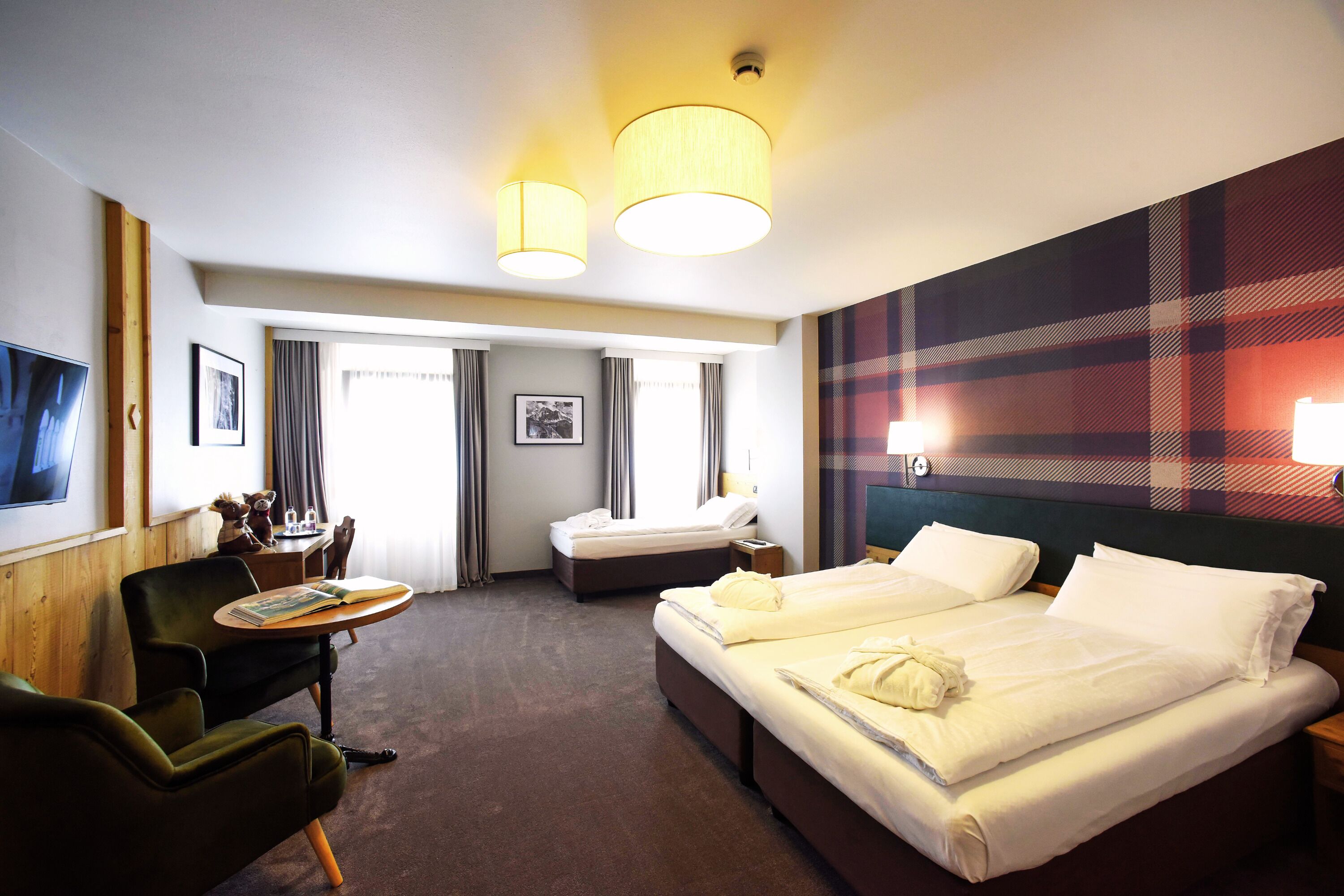 A hotel room with two beds, a desk, a chair, and a television.