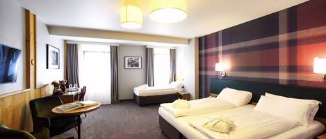 A hotel room with two beds, a desk, a chair, and a television.