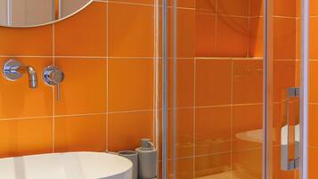 A bathroom with a white sink, a round mirror, and orange tiled walls.