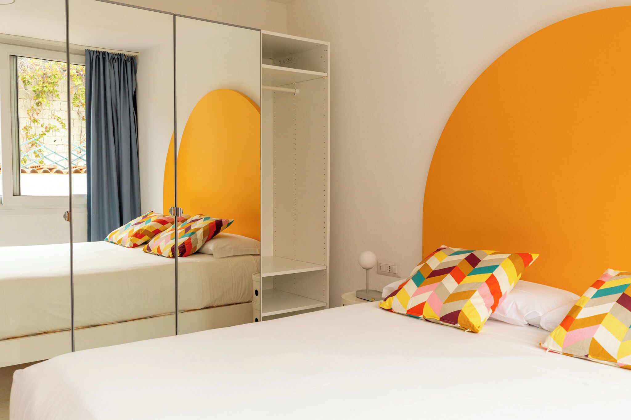 Un dormitorio con cama, armario y ventana con cortinas.