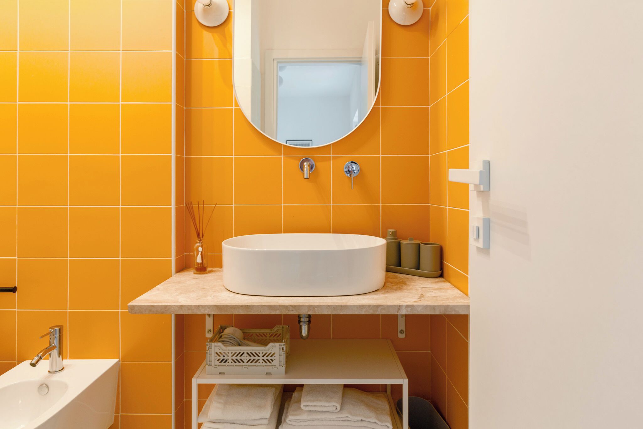 A bathroom with a white sink, a mirror, and orange tiles.