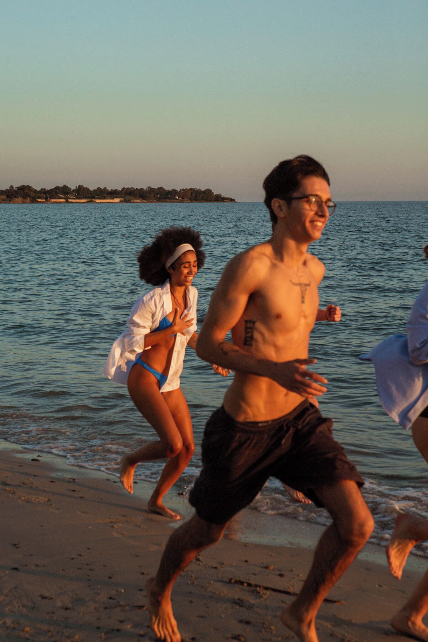 A beach scene with people running along the shore.