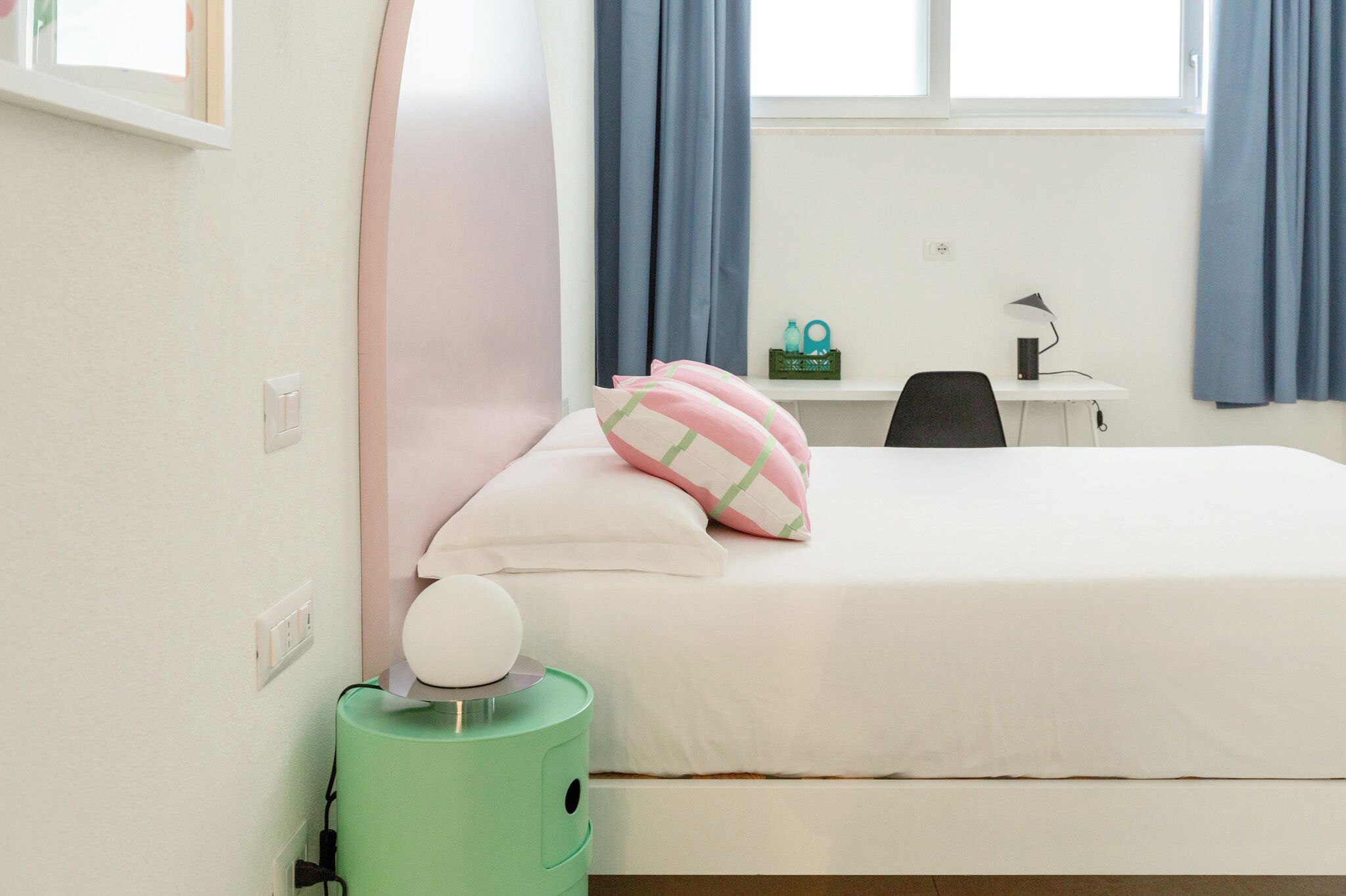 A neatly arranged bedroom with a bed, a desk, and a chair.