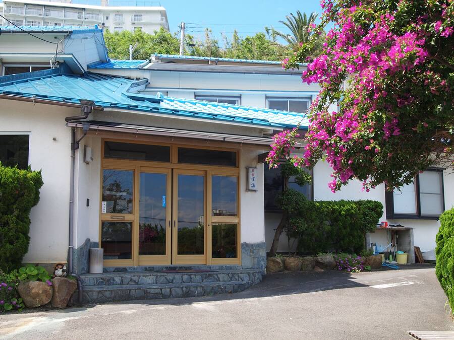 A building with a blue roof, large glass doors, and a stone base.