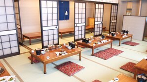 Una habitación japonesa tradicional con suelo de tatami, mesas bajas y puertas correderas.