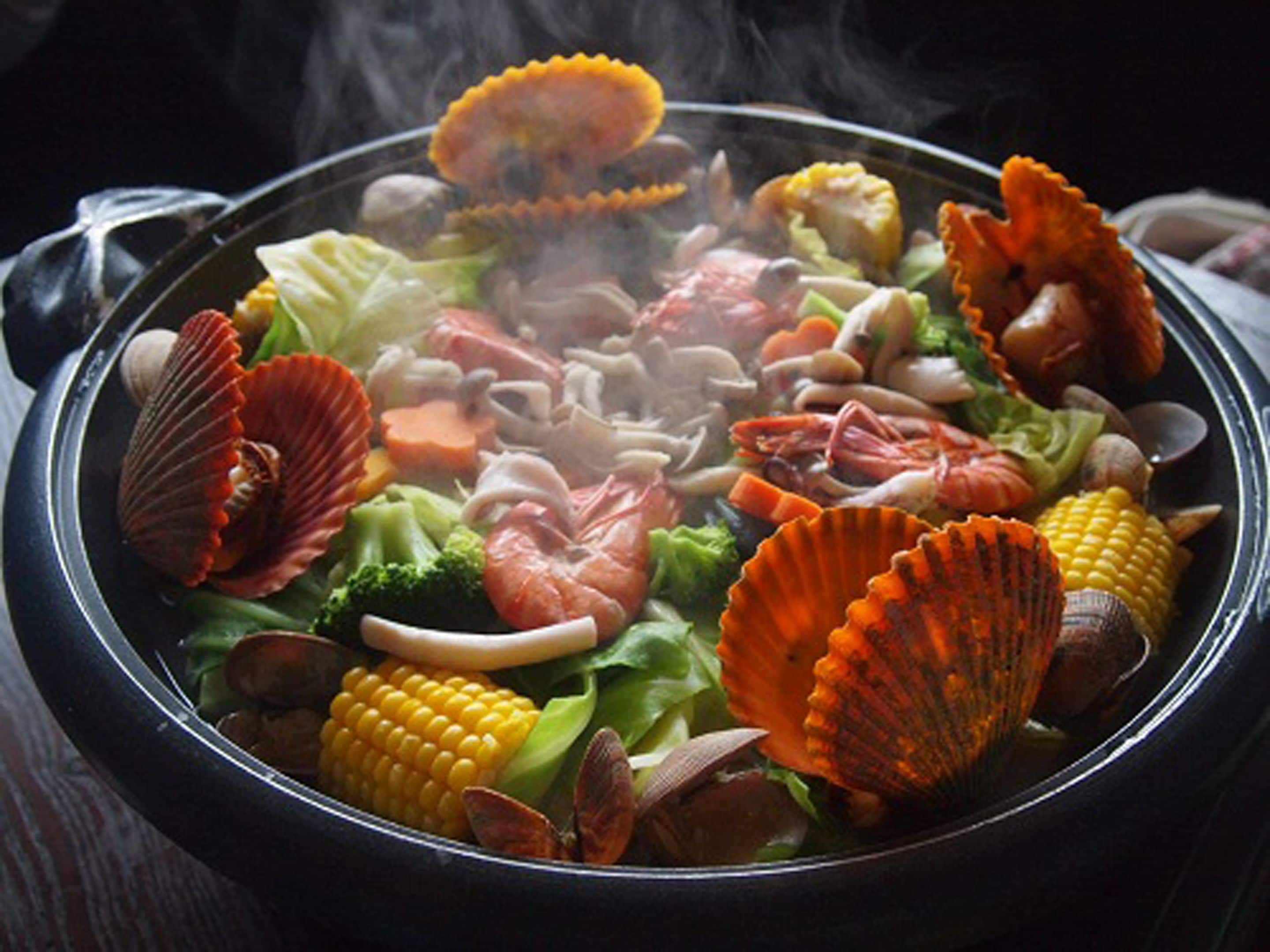 A seafood hot pot with various ingredients like shrimp, clams, and vegetables.