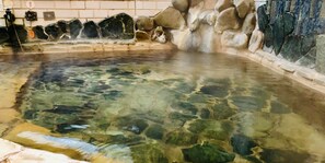 Una piscina cristalina con rocas visibles y un muro de azulejos.