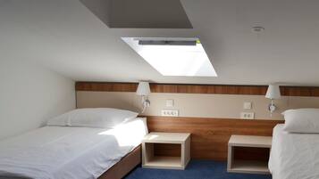 A hotel room with a skylight, two beds, bedside tables, and a wooden headboard.