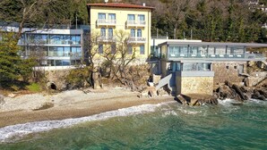 Ein Küstengebäude mit Natursteinfassade, einem Balkon und freiem Blick auf das Meer.