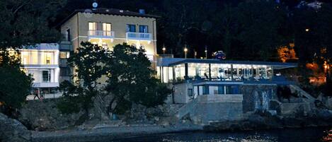 A waterfront property with a large building featuring multiple balconies and a glass facade.