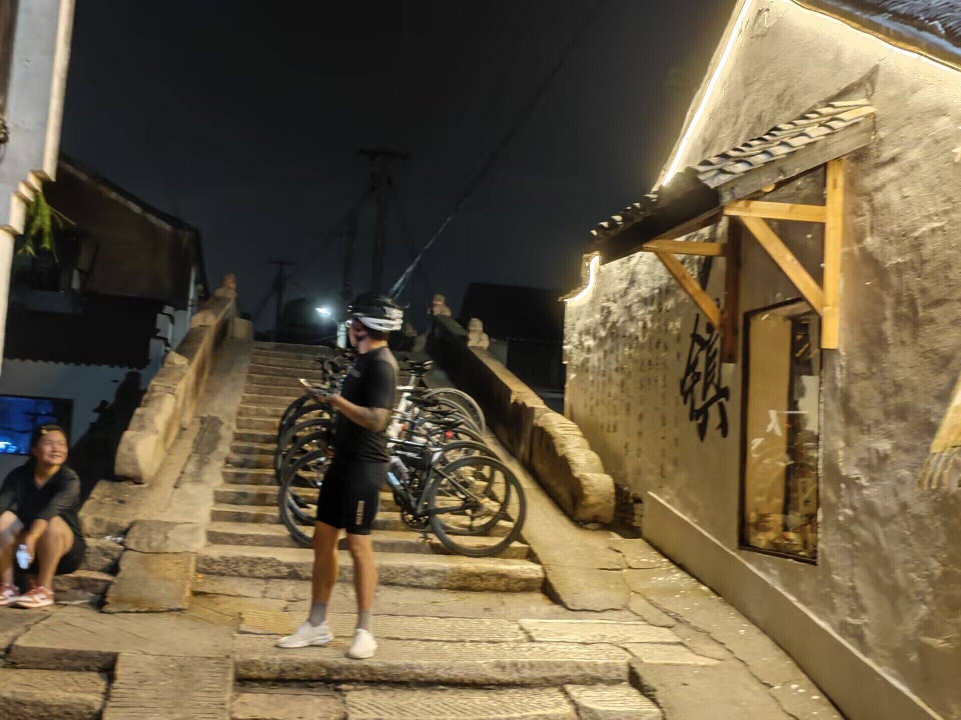 A person standing on a stone staircase in a narrow alleyway with bicycles parked against a building.
